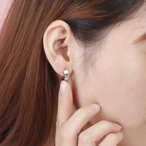 Close-up of elegant silver letter engraved zircon earrings on female model