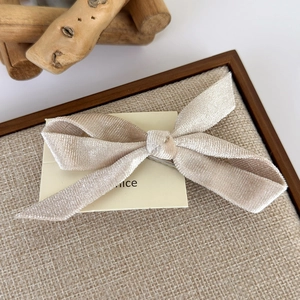 Detail of beige velvet bow hair clip with fine texture on elegant display card