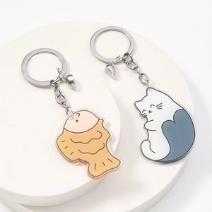 Close-up of cat and fish acrylic keychains with magnetic heart connectors on white display