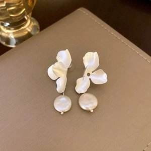 Elegant silver petal earrings with white baroque pearl pendants on beige leather surface