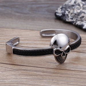Nahaufnahme eines Herren-Totenkopf-Armreifs mit schwarzem Leder auf einer Holzfläche