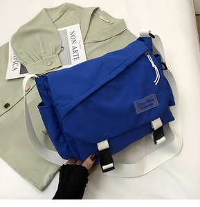 Detail of blue messenger bag featuring adjustable white strap and plastic buckle closure