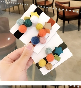 Dettaglio di tre graziose mollette in peluche nero, marrone e verde con stelle colorate