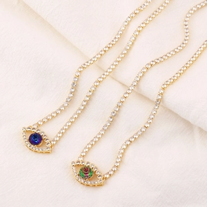 Detail of gold evil eye pendants with zircon pave and blue center stones on chains