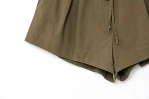 Detail of olive green fabric texture and drawstring closure on summer shorts