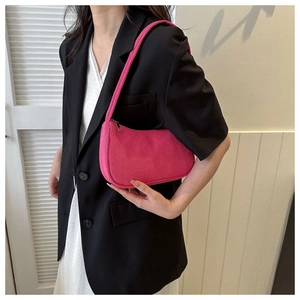 Pink corduroy baguette shoulder bag styled by a model in a minimal indoor setting