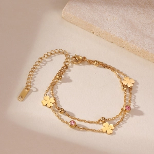 Detailed macro view of gold double-layer chain with clover charms and pink zircon stones