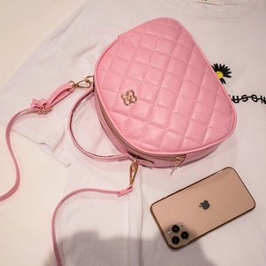 Pink quilted crossbody bag with golden flower detail and smartphone size reference