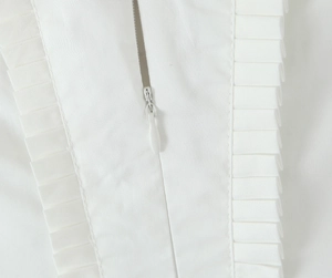 Detail view of seamless hidden zipper and elegant ruffle texture on a white halter dress