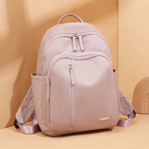 Mochila de nailon rosa claro para mujer con cremalleras doradas y compartimentos de viaje