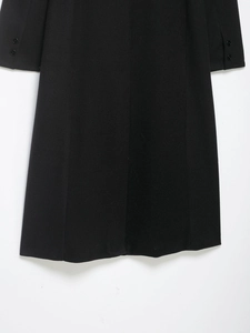 Detail of black wool coat sleeve showing decorative buttons and high-quality fabric texture