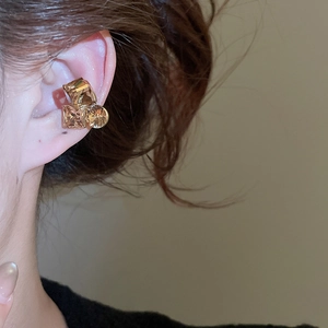 Close-up of champagne gold ear cuff with three geometric crystals worn on human ear