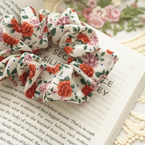 Detailed shot of fabric floral scrunchie with rose patterns placed on an open book