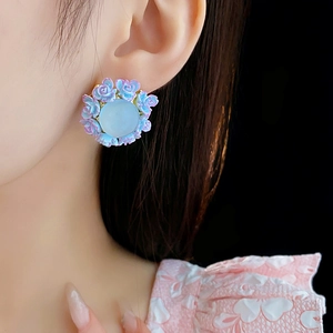 Detailed view of floral stud earrings with blue purple gradient petals on a model