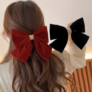 Detail showing red and black velvet bow hair clips with metal rings on a model