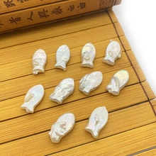 Macro shot of 10 fish-shaped iridescent white freshwater pearls on a bamboo scroll