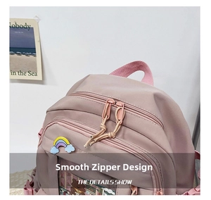 Detail view of smooth double zippers and rainbow cloud badge on a pink school backpack