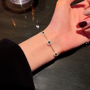 Elegant gold bracelet featuring pearl flowers with green zircon centers on a female wrist