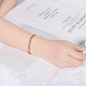 Gold Figaro chain bracelet for men and women worn by model over a book background