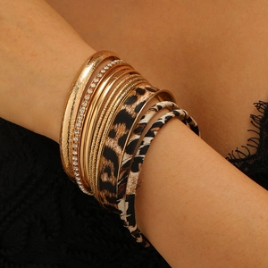 Macro shot of layered gold metal bracelets and leopard print bangles with rhinestone details