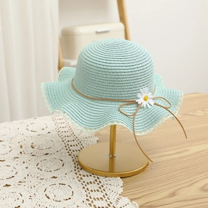 Detail of mint green straw hat with white daisy floral and lace wavy rim on metal stand