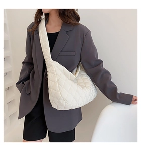 Macro detail of creamy white quilted cloud bag showing soft padded diamond texture and wide strap