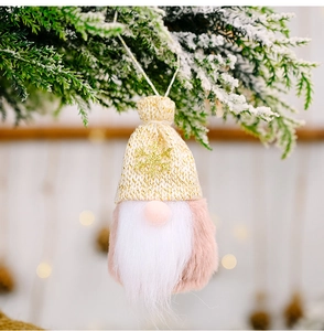 Detail eines Weihnachtsgnoms mit goldener Paillettenmütze an einem verschneiten Tannenzweig