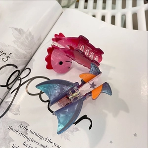 Detail shot of acrylic dinosaur hair claws in pink and purple on a vintage book