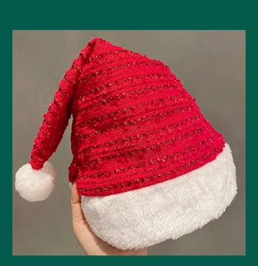 Close-up of red glitter Christmas hat with thick white faux fur trim and soft pom-pom