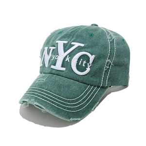 Detailed macro view of vintage olive baseball cap showing frayed NYC embroidery and fabric
