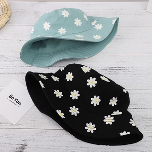 Detail of floral daisy print bucket hats in black and mint green on wooden background