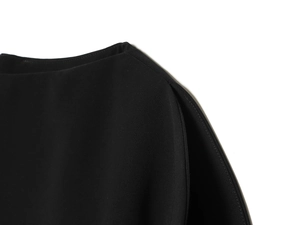 Détail de la couture du col rond et de l'épaule bouffante sur haut noir minimaliste