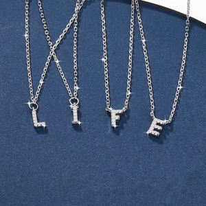 Close-up of four silver 925 necklaces with crystal-encrusted L, I, F, E letter pendants