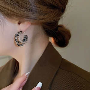 Close-up of double layered tortoise shell hoop earrings worn with retro brown blazer