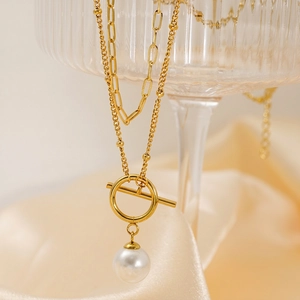 Detailed shot of double-layer gold necklace with OT buckle and white pearl pendant