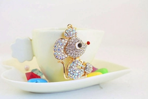 Detail of cute gold mouse keychain with colorful rhinestones on a white saucer