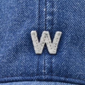 Macro shot of embroidered white W letter patch on vintage washed blue denim baseball cap