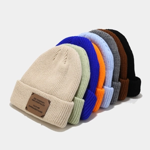 Group of rib-knit beanies in multiple colors with leather patches for men and women