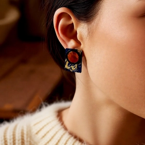 Close-up of vintage resin square leather earrings on a model in a cozy white sweater