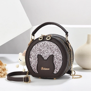 Brown round crossbody bag with cat ear design and silver glitter on a studio background