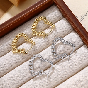 Détail de boucles d'oreilles en forme de cœur dorées et argentées avec motifs ajourés