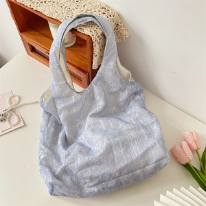 Détail du sac fourre-tout en toile bleu clair avec motifs nœuds roses et dentelle
