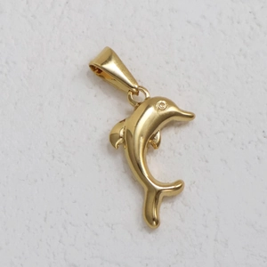 Detailed view of a 24K gold plated stainless steel dolphin pendant on a textured surface