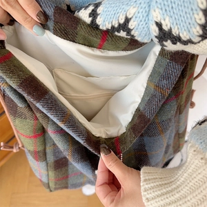 Detail of wool plaid backpack interior featuring white fabric lining and zipper pockets