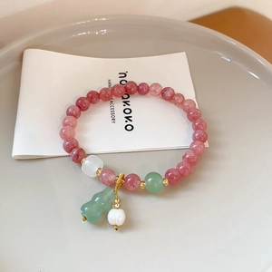 Detail of beaded bracelet with pink strawberry quartz white pearls and green gourd pendant