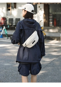 Outdoor street shot of a beige utility waist bag worn by a model in urban style