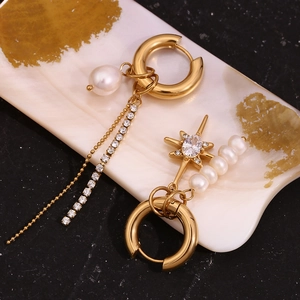 Detail of asymmetrical gold star earrings with freshwater pearls and tassel rhinestones