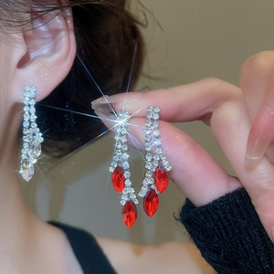 Detailed view of silver tassel earrings with sparkling crystals and red teardrop gems