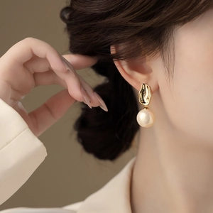 Detailansicht eleganter großer Perlenohrringe mit minimalistischen goldenen Steckern