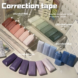 Detail view of colorful gradient correction tapes in pastel pink, blue, and green on a desk